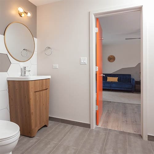 bathroom vanity with door open leading into living room with blue couch