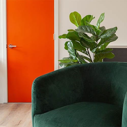 green chair in foreground with orange entrance door in background